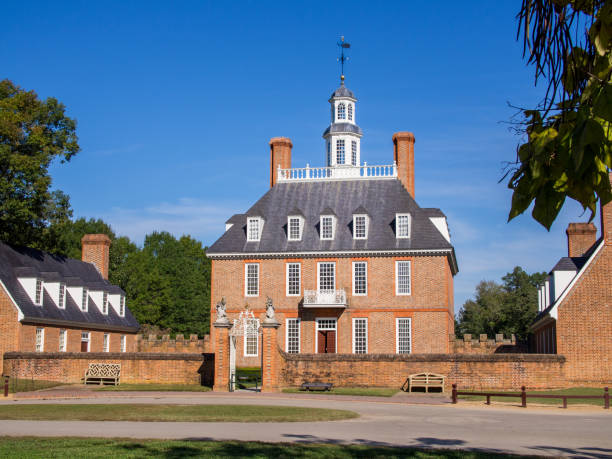 The Governor's Palace with lawn in front and a clear blue sky above in historic colonial Williamsburg, Virginia. In historic colonial Williamsburg, Virginia, the Governor's Palace with its front lawn and clear blue sky above stands as a magnificent sight. governor's palace williamsburg stock pictures, royalty-free photos & images