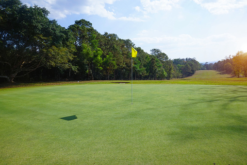 Background of evening golf course has sunlight shining down at golf course in Thailand. Nice scenery on a golf course at a late summer afternoon.