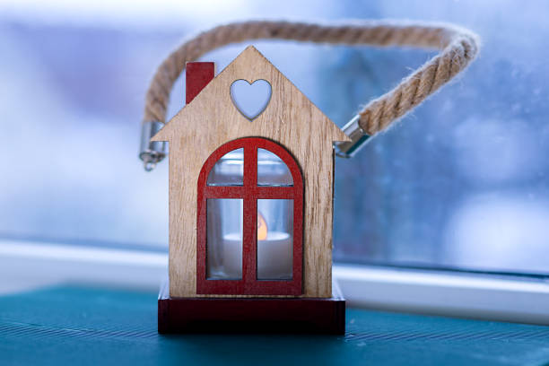 Christmas house with candle inside on the window, blue background