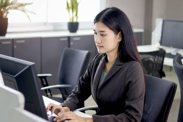 istock Serious beautiful Asian woman officer typing desktop computer while sitting at office desk. Concentrate female worker working at workplace, hardworking and busy office lady employee staff at office. 1669904066