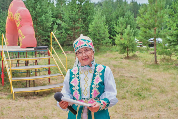 azjatycka dojrzała kobieta w stylizowanych strojach tatarskich w pobliżu sceny. gospodarz koncertu na festiwalu wiejskim. - attractive female looking at camera outdoors rural scene zdjęcia i obrazy z banku zdjęć