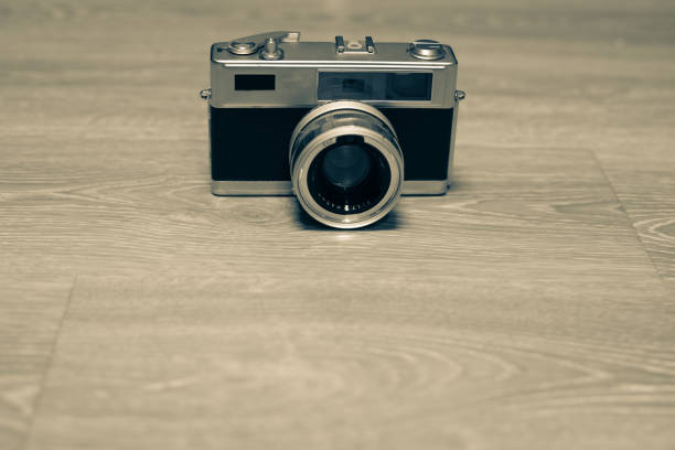 A well-preserved single-lens reflex camera features a black body, chrome accents, and a square lens hood,\nresting against a warm-toned background.
