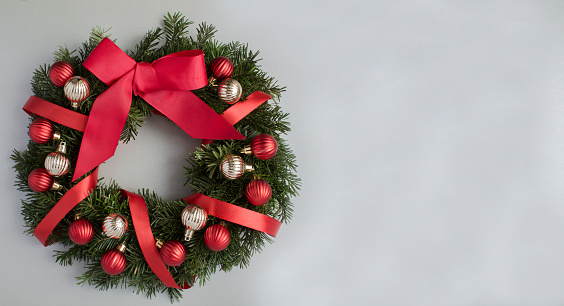 Christmas ring or wreath with red and gold bead on the gray  background. Copy space. Top view.