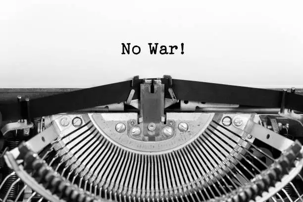 Photo of No War phrase closeup being typing and centered on a sheet of paper on old vintage typewriter mechanical