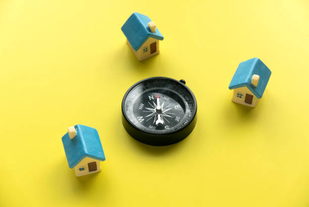istock Miniature house and a compass over a yellow background. 1669969131