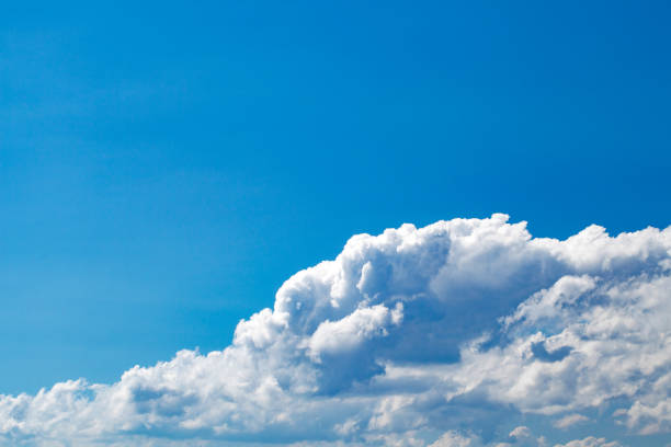 istock Cumulus clouds close-up on blue sky on clear day, glare from the sun 1669980937