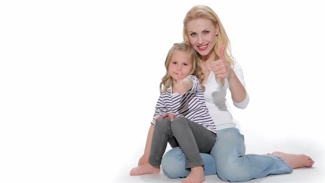 Female kid and her mom show their thumbs