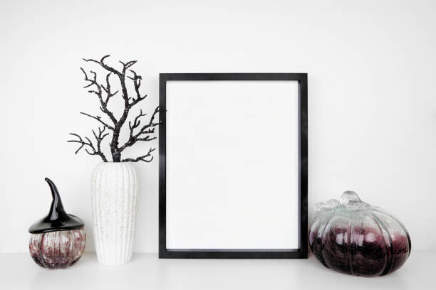 istock Halloween mock up black frame on a white shelf with black branches and glass pumpkin decor 1670042866