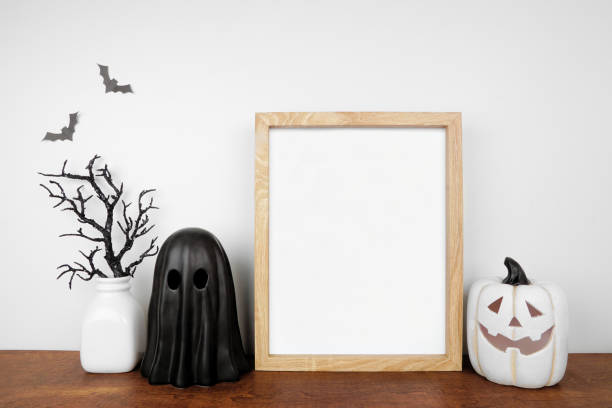 istock Halloween mock up wooden frame on a wood shelf with black branches, ghost and jack o lantern decor 1670043393