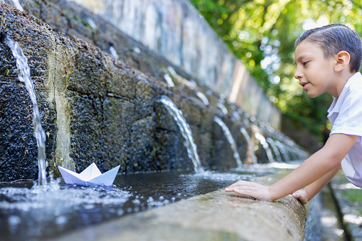 Child playing with paper boat in the water