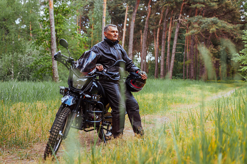 Senior man leaning on motorcycle on desert road