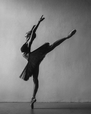 Beautiful ballerina dancing on light grey background. Dark silhouette of dancer