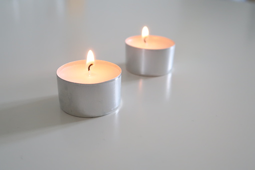 Lit Tealights on a White Table, Minimalistic White Nordic Home Decor, warm tone candlelights, blurry background, focused picture