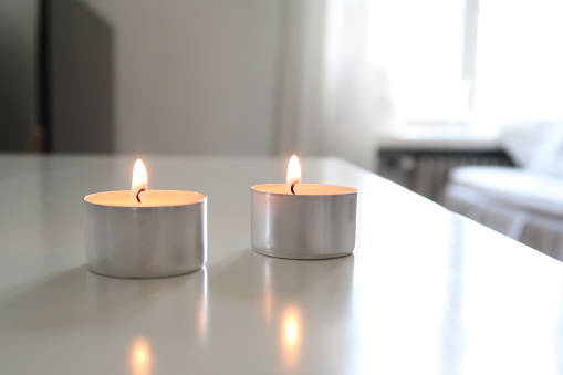 Lit Tealights on a White Table, Minimalistic White Nordic Home Decor, warm tone candlelights, blurry background, focused picture