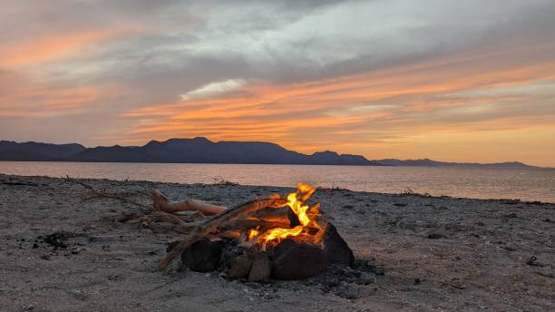 istock Tranquil sunrise scene featuring a beach bonfire burning at sunset 1670219279