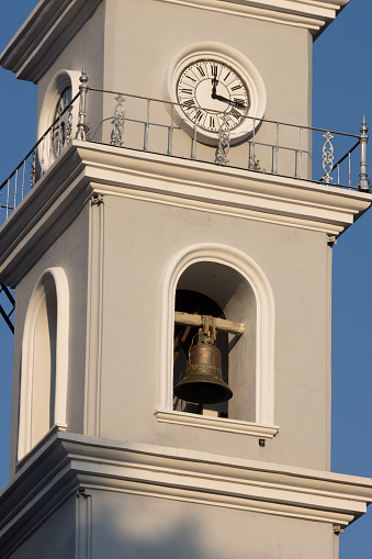 Tower with bell and clock of catholic church on blue sky background
