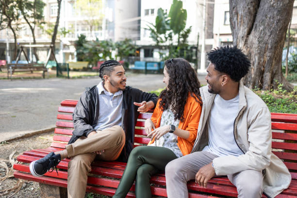istock Group of friends talking on a park bench 1670261685