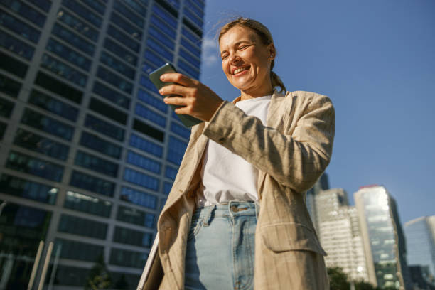 istock Stylish woman freelancer using phone whiile standing on modern office background 1670262190