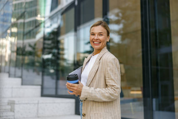 istock Positive female manager drinking coffee during break time near office building. High quality photo 1670295448