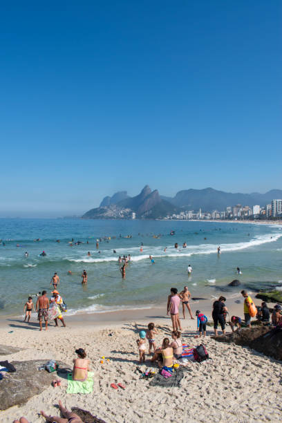 rio de janeiro, brasilien: menschen sonnen sich, schwimmen und surfen am strand von ipanema - ipanema district stock-fotos und bilder