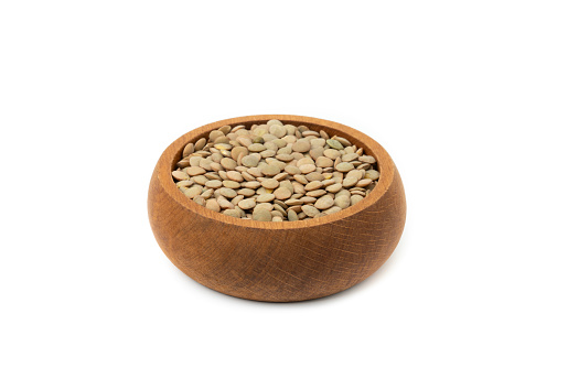 Green lentils in a wooden bowl isolated on a white background