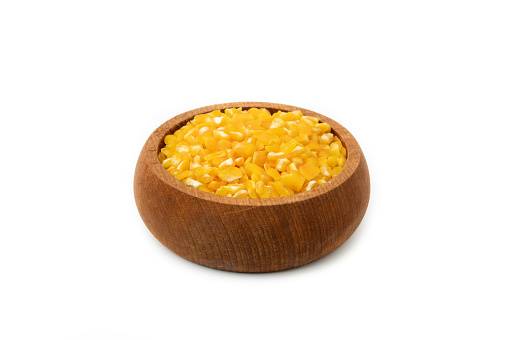 Wooden bowl full of Yellow splintered corn isolated on white background.