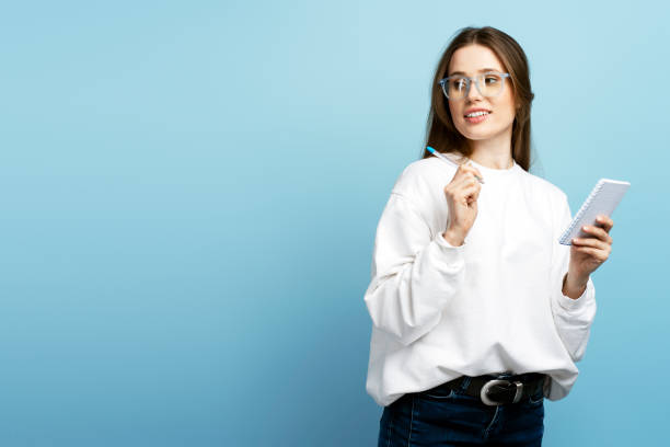 Smiling student wearing stylish eyeglasses holding pen, notebook, taking notes. Education concept