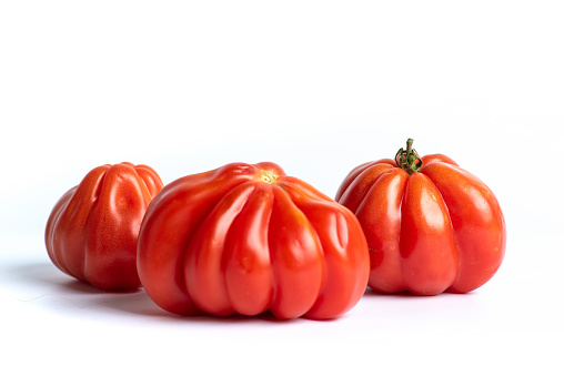 Three juicy, ripe, red tomatoes on a white background