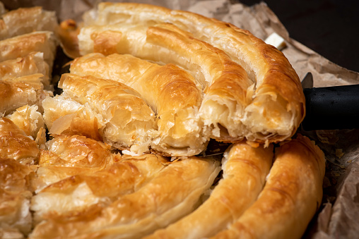 Freshly baked traditional Greek pie - snail with cheese. Roll with a filling made of cubes of cheese and eggs.