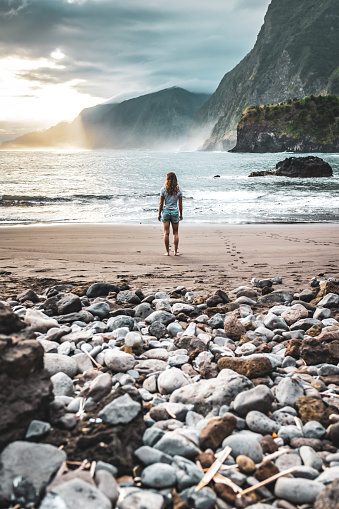 Description: Woman walking on beautiful beach and enjoying the atmospheric morning atmosphere. Seixal beach, Madeira Island, Portugal, Europe.