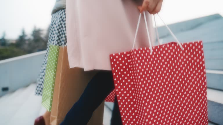 SLO MO Two unrecognizable women in stilettos carry shopping bags as they walk up the stairs in the city