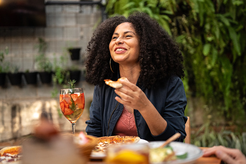 Mid adult woman talking and eating at restaurant