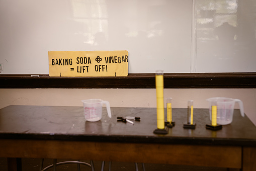 Black students attend a Science class at school.  They sit at desks to conduct science experiments using science tools to measure volume of water.