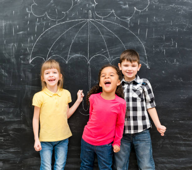 istock three funny children with umbrella drawn on the blackboard 1670667540
