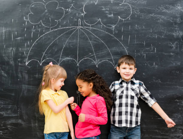 istock three funny children with umbrella drawn on the blackboard 1670667541