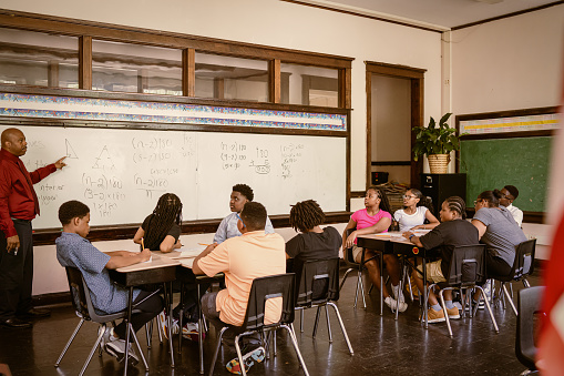 Junior-high Black students attend a math class at school.  They participate in math lesson and solve math problems.