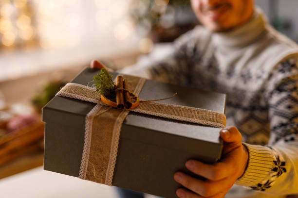 istock Creative young man showing you a rustic Christmas gift box that he decorated 1670731244
