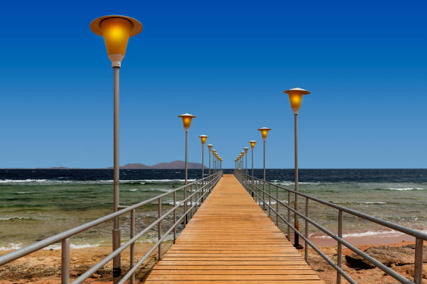 Wooden pier with streetlights on sea cost at dusk.