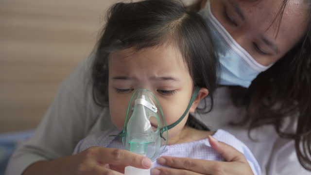 Asian little girl with RSV bronchitis symptoms getting nebulizer treatment or inhaler. Asthma treatment