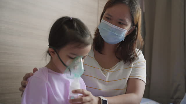 Asian little girl with RSV bronchitis symptoms getting nebulizer treatment or inhaler