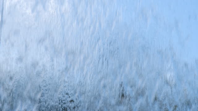 Water jets on a glass waterfall flow down creating a beautiful background.