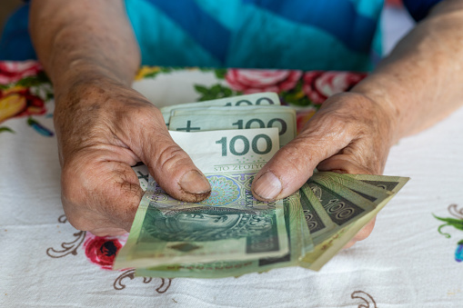 An old woman holds 100 Polish zloty banknotes in her hands, Polish money, Concept, Pension, allowance, help for the elderly