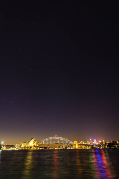 l’opéra et le harbour bridge illuminés la nuit à sydney, en australie - sydney harbor bridge sydney opera house vertical australia photos et images de collection