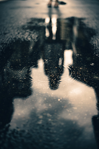 After the rain, there is a puddle on the ground, and within a ripple, there is a reflection of a person