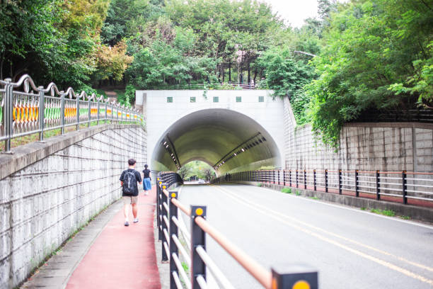 Cheonan City, South Korea - September 9, 2023:  South Korea now experiences traffic congestion even in small towns. To solve this problem, tunnels passing from one village to another are being drilled in various places. This tunnel is called Bongseosan Tunnel in Cheonan-si, Chungcheongnam-do. A citizen and a student are walking to school. (Photo by Young Jin Lee)