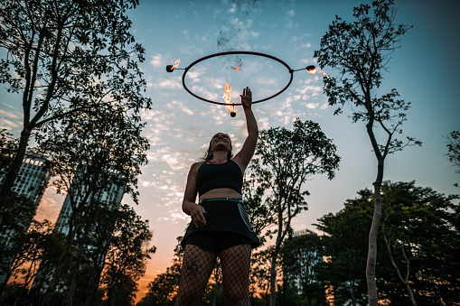 Fire spinner practicing her routine with a hoop in a public park