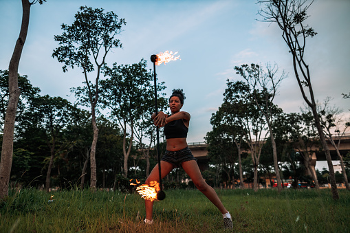 Fire spinner practicing her routine with a double staff in a public park