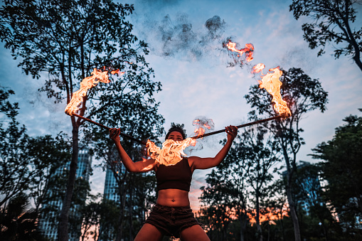 Fire spinner practicing her routine with two double staffs in a public park