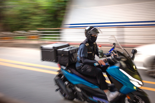Cheonan City, South Korea - September 9, 2023: Demand for delivery has surged in the aftermath of COVID-19. The number of people working as delivery workers has also increased in South Korea. A delivery biker wearing a mask is passing through a tunnel at high speed. (Photo by Young Jin Lee)