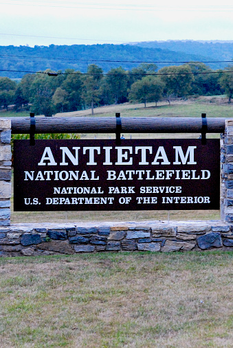 Sharpsburg, Maryland, USA - September 9, 2023: A sign welcomes visitors to the Antietam National Battlefield at dusk as mist covers the distant mountains.